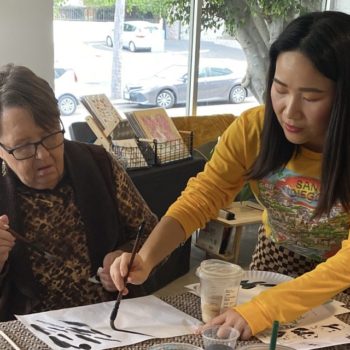 an artist teaching an old woman to paint