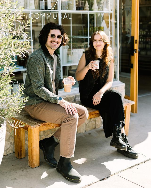 man and woman sitting on a bench drinking coffee 