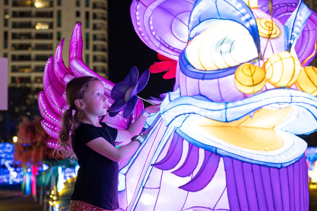 a kid touching a glowing dragon sculpture