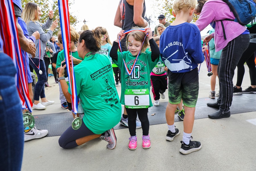 kid putting on her joggin' for frogmen medal