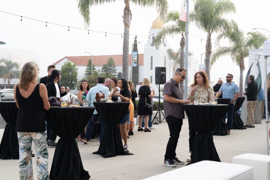 a group of people standing around drinking and eating