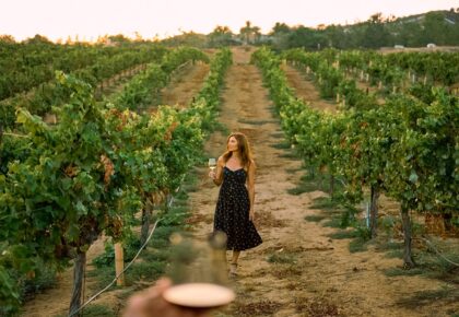 a woman walking in the middle of a vineyard