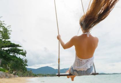 woman riding a swing on the beach