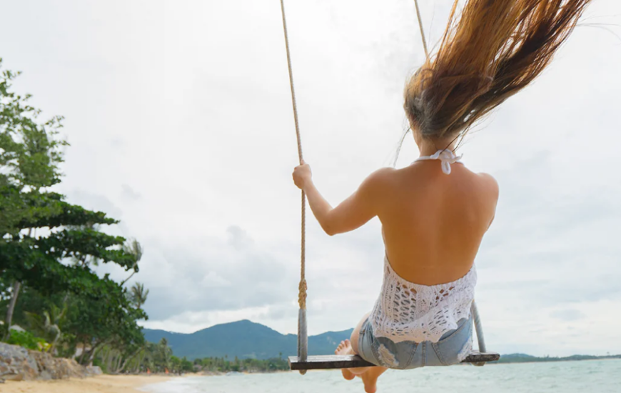 woman riding a swing on the beach