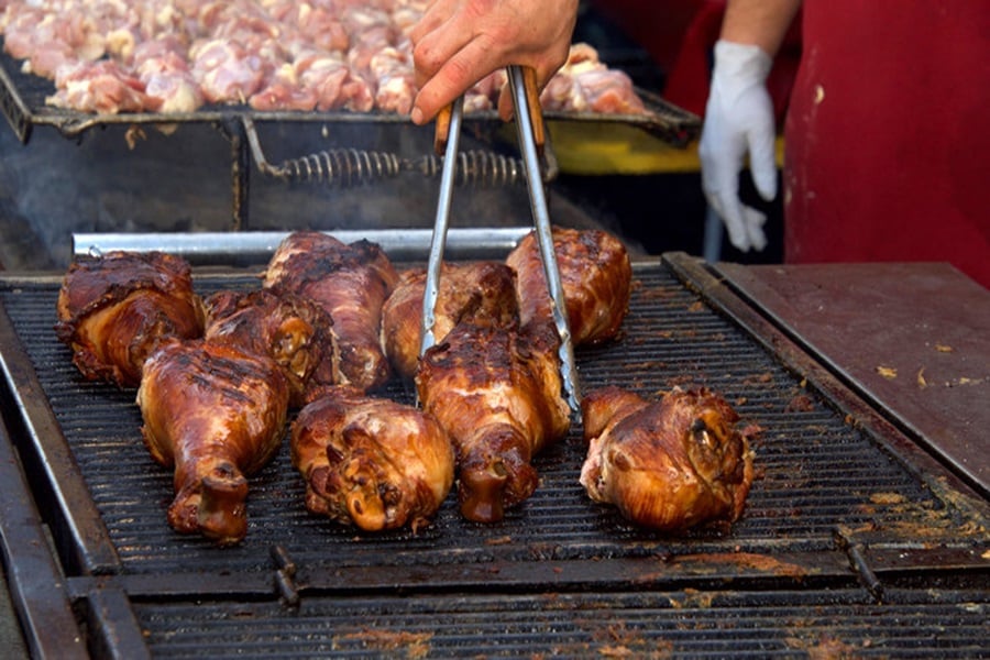Chicken grilling on an outdoor bbq, hand turning meat